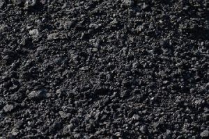 The background is the texture of small black fragmented stones in the form of asphalt crumbs A lot of building material for industrial repair of black coal roads High quality photo