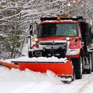 Red snow plow working a snow bank